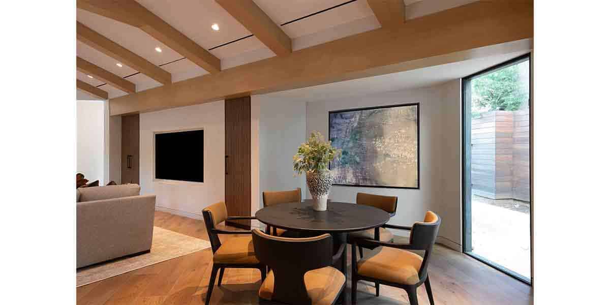 Contemporary living room interior with wooden beams and large glass windows.