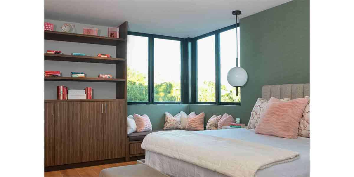 Contemporary bedroom with green walls, large windows, and a cozy seating nook with cushions.