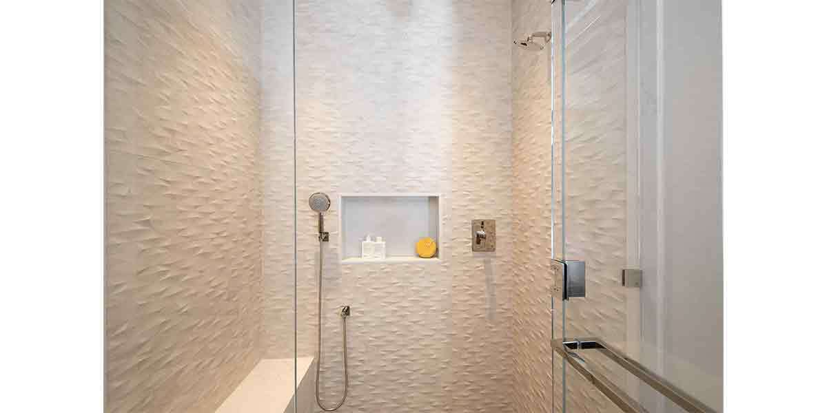 Contemporary shower with textured wall tiles and built-in niche for toiletries.