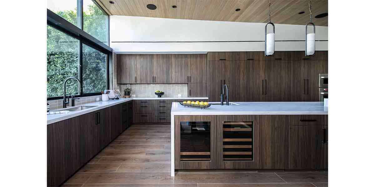 Modern kitchen with dark wood cabinets and white countertops, featuring sleek design and ample natur.