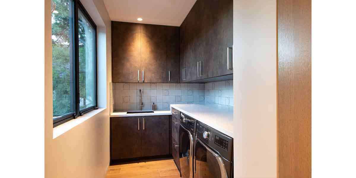 Modern kitchen with dark wood cabinets, large window, and laundry area.