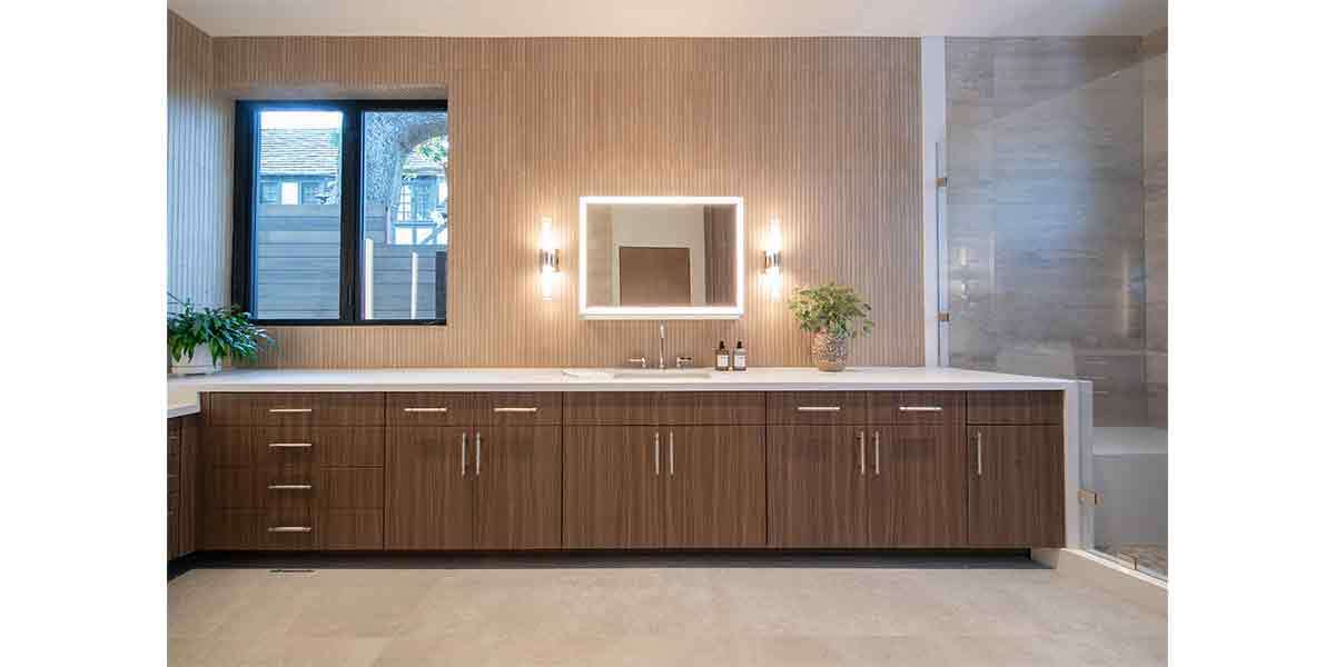 Modern bathroom vanity with wooden cabinets and illuminated mirror.