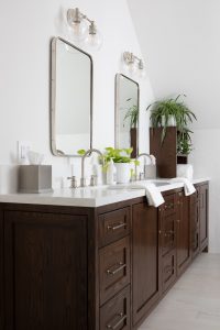 Bathroom vanity with dual mirrors, modern lighting, and lush green plants for a stylish interior des.
