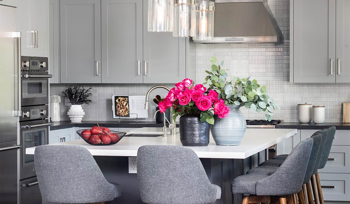 Contemporary gray kitchen with floral centerpiece and sleek cabinetry.