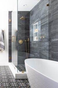 Elegant gray tiled bathroom featuring a glass-enclosed shower with gold fixtures and a freestanding.